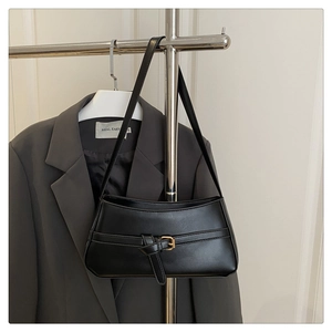 Detail of black underarm bag featuring decorative knot strap and golden metal buckle