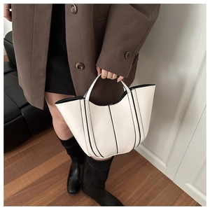 Sac seau beige minimaliste avec bordures noires contrastées dans un cadre de mode élégant