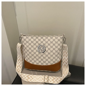 Detail of monogram bucket bag featuring a round M logo and geometric woven shoulder strap