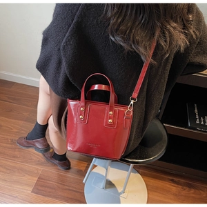 Chic red patent leather mini tote bag with gold rivets shown in a lifestyle setting