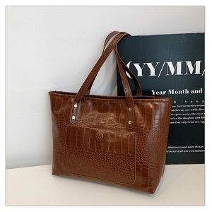 Detail of dark brown crocodile embossed tote bag with vintage texture and outer pocket