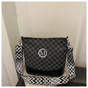 Close-up of bucket bag featuring monogram print and wide geometric woven shoulder strap