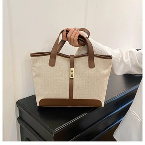 Détail d'un sac cabas en toile avec garniture en cuir marron et boucle en métal doré