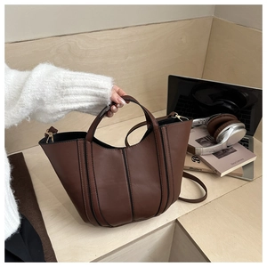 Détail du sac seau marron avec surpiqûres noires et anneau en D sur le côté du sac