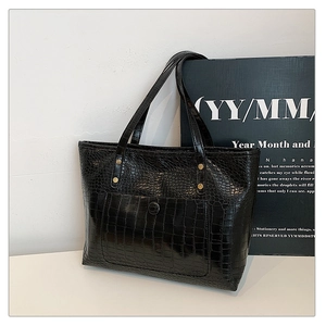 Detail view of black crocodile pattern tote bag with magnetic flap pocket and gold rivets