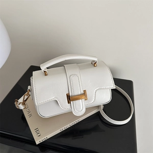 Retro white crossbody bag with lychee texture and gold buckle on a sleek black stand