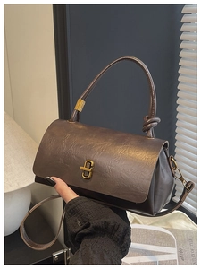 Detail of dark brown vintage textured handbag with gold twist lock and leather strap