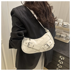 Detailed view of white quilted faux leather baguette bag with silver buckles and strap