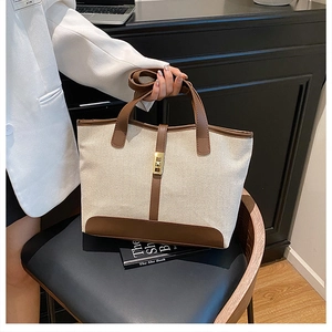 Détail du sac cabas en toile et cuir marron avec boucle dorée sur chaise noire