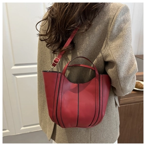 Détail du sac seau rouge avec passepoil noir 3D et texture en cuir synthétique lisse