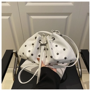 Close-up of a white bucket bag with silver rivet details and drawstring closure