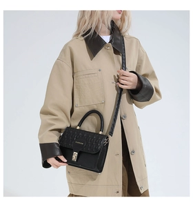 Detail of black faux leather handbag with gold twist lock and Fashion logo engraving