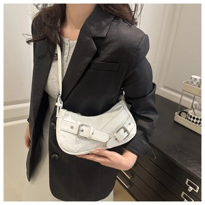 Detailed view of a white crescent shoulder bag with dual buckle straps on a model