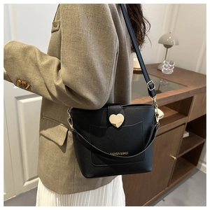 Detail view of black lychee grain leather bucket bag featuring gold heart buckle and logo