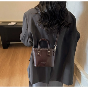 Detail of dark brown leather mini tote with gold studs and removable shoulder strap