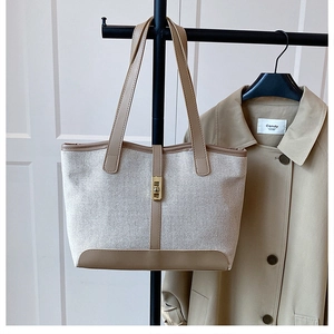 Détail du sac cabas en toile avec garniture en cuir marron et fermoir tournant doré