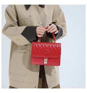 Detail of red quilted handbag with wave texture, golden buckle and top handle