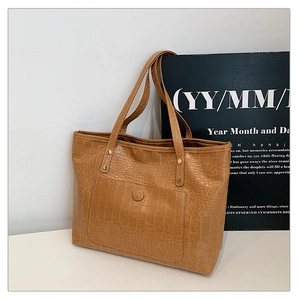 Macro shot of caramel crocodile pattern PU leather tote bag with gold metal rivets