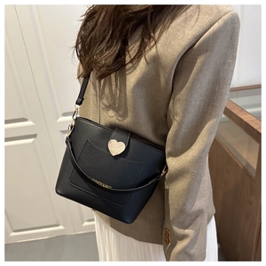 Détail du sac seau noir en cuir grainé avec un grand fermoir cœur doré et bandoulière