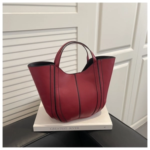 Détail du sac seau en cuir rouge foncé avec finitions noires et doubles poignées