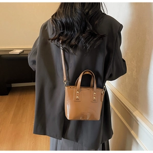 Detailed view of brown PU leather bucket bag with gold rivets and adjustable shoulder strap