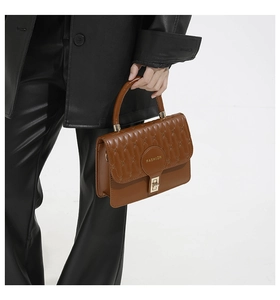 Close-up of brown leather handbag featuring quilted stitching and golden hardware lock