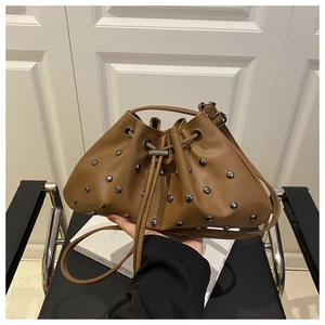 Detailed close-up of brown bucket bag featuring silver rivets and drawstring closure