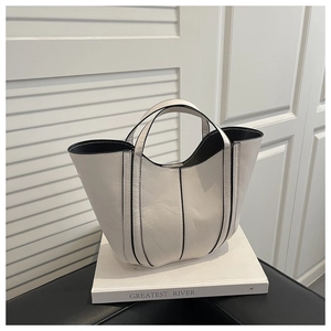 Détail du sac seau crème à panneaux avec bords noirs contrastés et doubles poignées