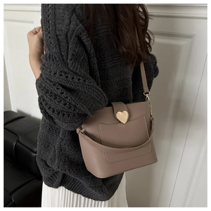Chic mocha brown bucket bag with gold heart buckle shown styled on a model's shoulder