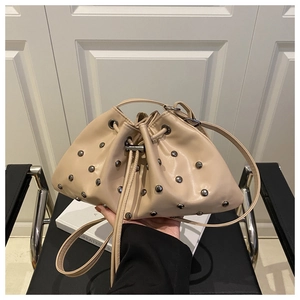 Detail of beige bucket bag with silver rivet studs and drawstring closure