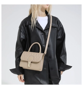 Detail of beige quilted shoulder bag with gold hardware and FASHION metal logo