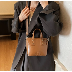 Detail of brown mini bucket bag with gold studs and Fashion & Leather embossed text