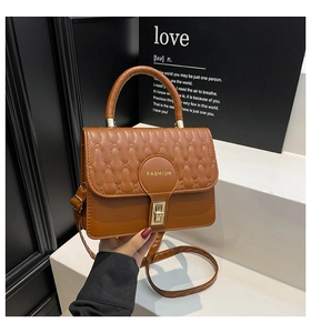 Detail of brown quilted leather crossbody bag with golden buckle and fashion emblem