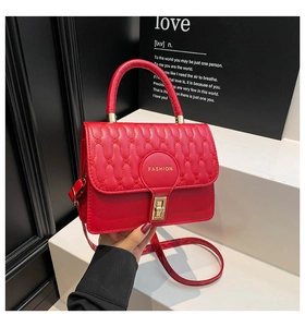 Detail of red quilted square bag with gold twist lock and Fashion text detail