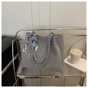 Detail of leopard print tote bag with woven handles and decorative blue floral scarf