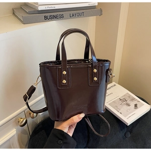 Close-up of brown glossy leather bucket bag with gold rivets and vintage hardware