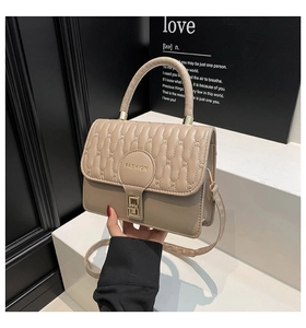 Close-up of beige quilted handbag featuring golden fashion logo and a square metal lock