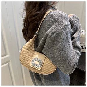 Détail du sac croissant plissé avec boucle en cristal porté par le mannequin