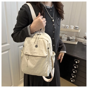 Lifestyle view of lightweight nylon backpack in off-white being worn by a model