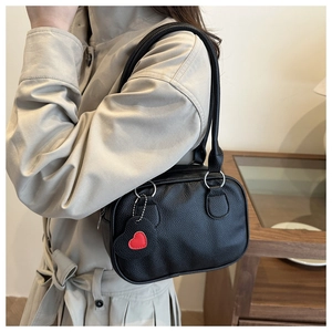 Close-up of black pebble leather shoulder bag with a red heart charm pendant