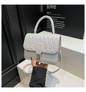 Macro detail of light grey quilted leather handbag with metallic lock and fashion text
