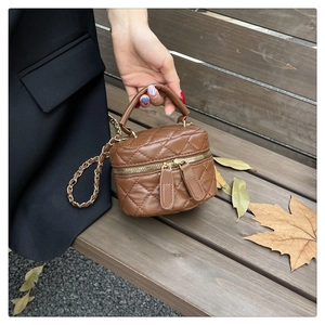 Close-up of caramel quilted leather box bag with gold zipper and chain strap detail
