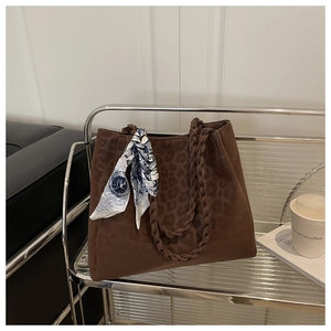 Detail of leopard print tote bag with woven handles and decorative vintage silk scarf