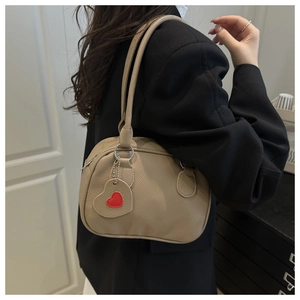 Detail view of khaki pebbled leather shoulder bag with cute heart charm on mannequin