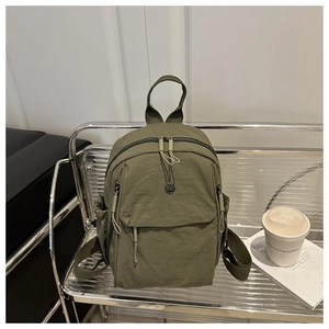 Detail of dark green nylon backpack with round logo on modern metal mesh chair