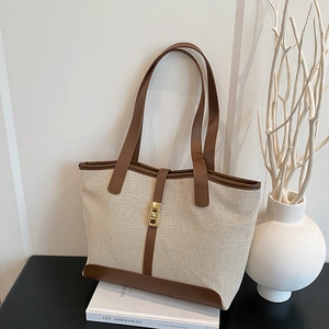 Chic beige canvas and brown leather tote bag with a golden metal twist lock closure