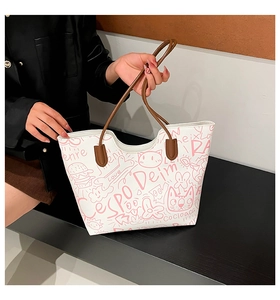 Dettaglio della borsa tote bianca con graffiti rosa cartoon e tracolle marroni sottili