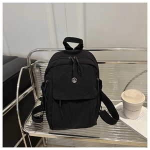 Detail of a black mini nylon backpack with silver logo on a chair for daily commute