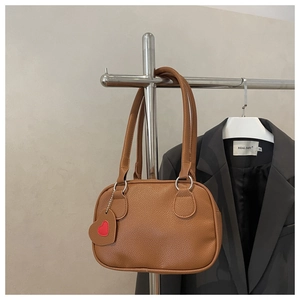 Close-up of caramel brown pebble leather handbag with a red heart embroidered charm