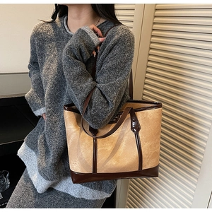 Detailed view of the vintage textured beige and brown leather tote bag on model